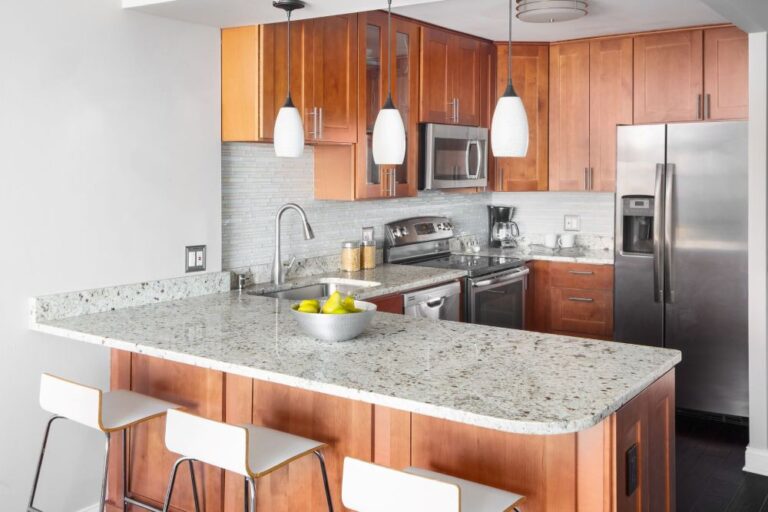 A kitchen with wooden cabinets, stone countertops, and modern fixtures