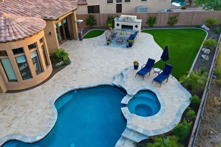 An Arizona residential backyard with a pool, deck chairs, and an outdoor eating area